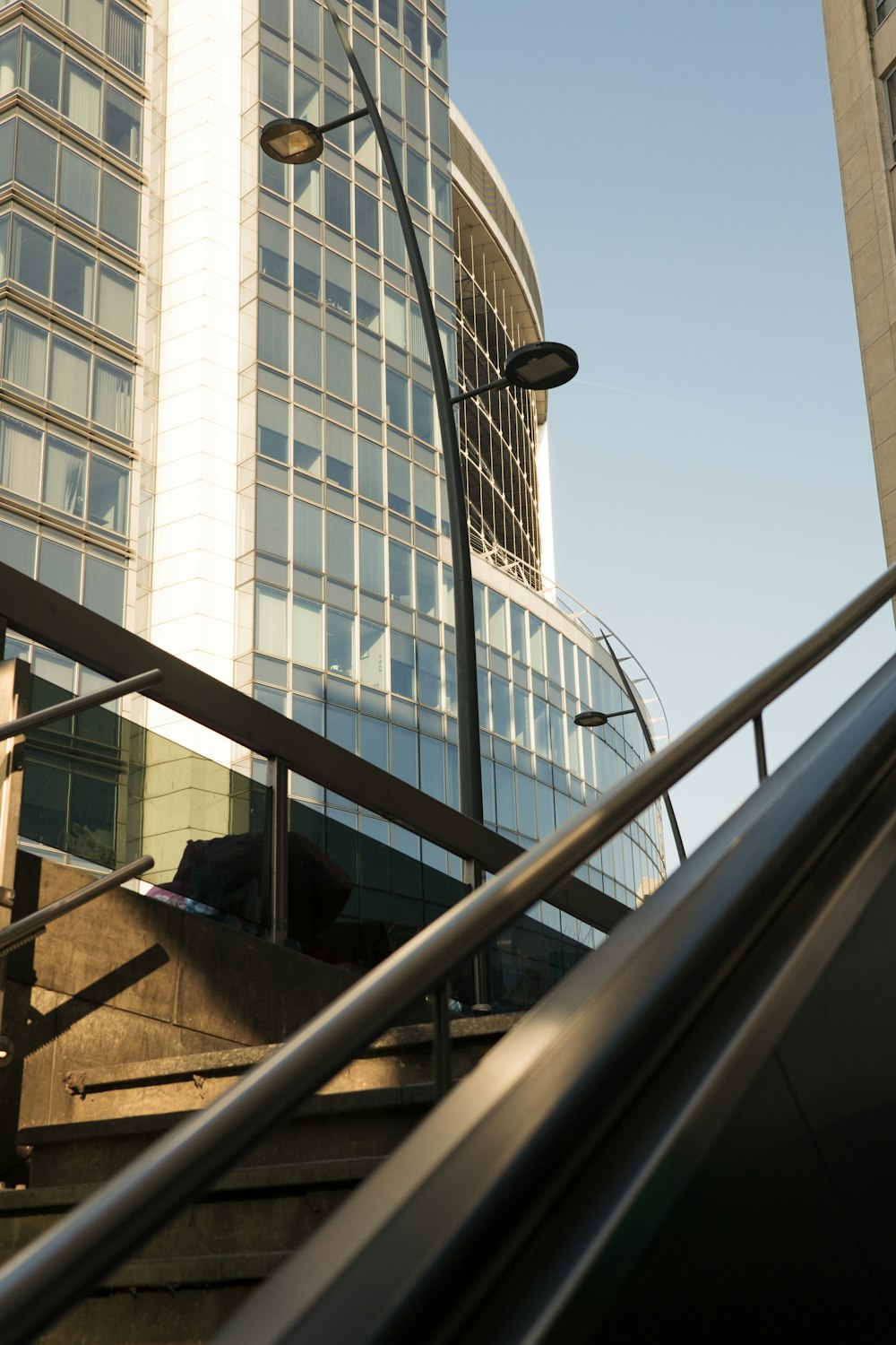 an escalator going up a set of stairs in front of a tall building