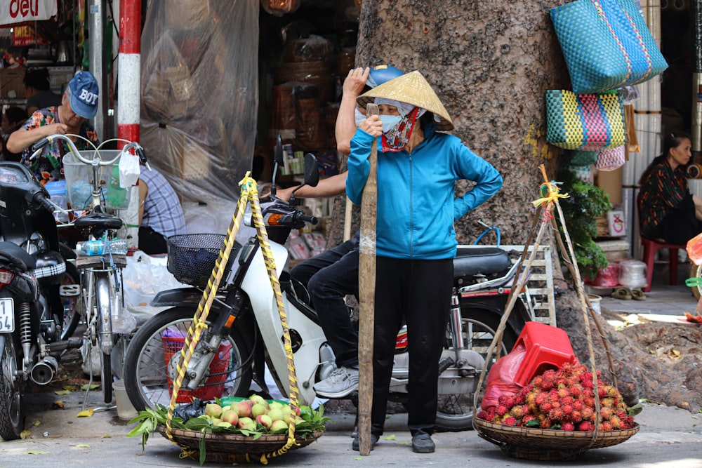 a woman standing next to a pile of fruit