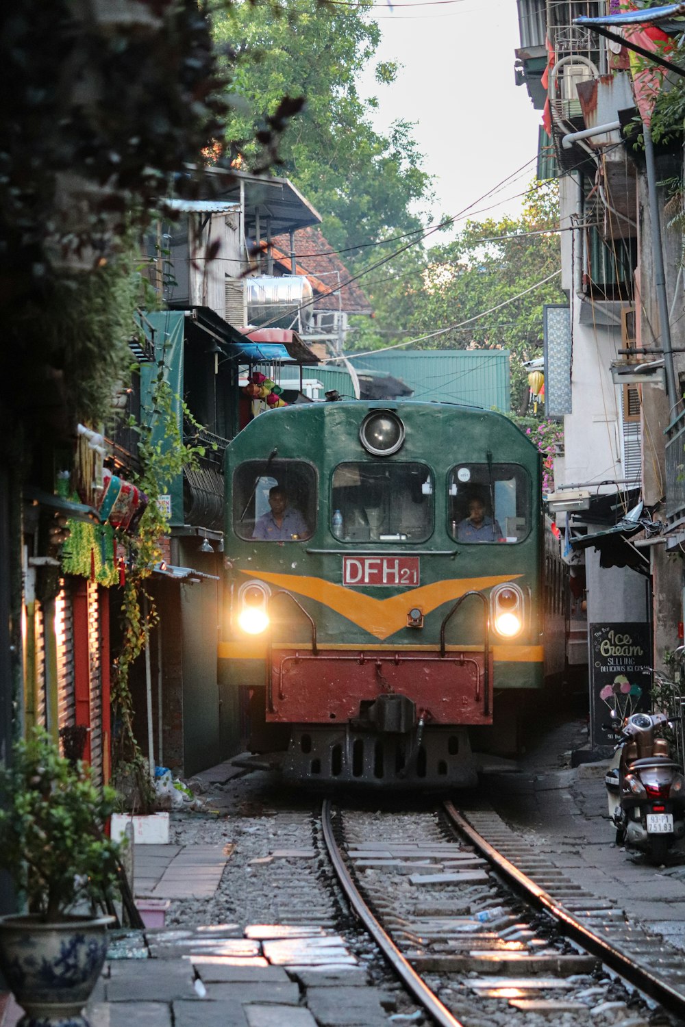 a green train traveling down train tracks next to tall buildings