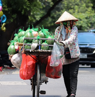 a woman pushing a cart filled with lots of produce