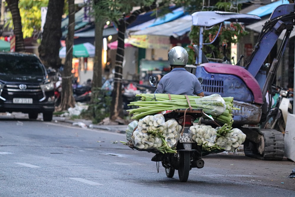 um homem andando de moto com um carrinho de legumes na parte de trás dele
