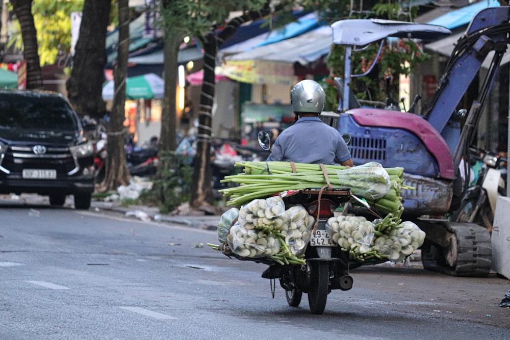 Un homme conduisant une moto avec un chariot de légumes à l’arrière