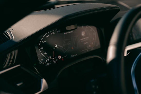 A close-up shot of a sleek car dashboard with a world map reflected on the windshield.