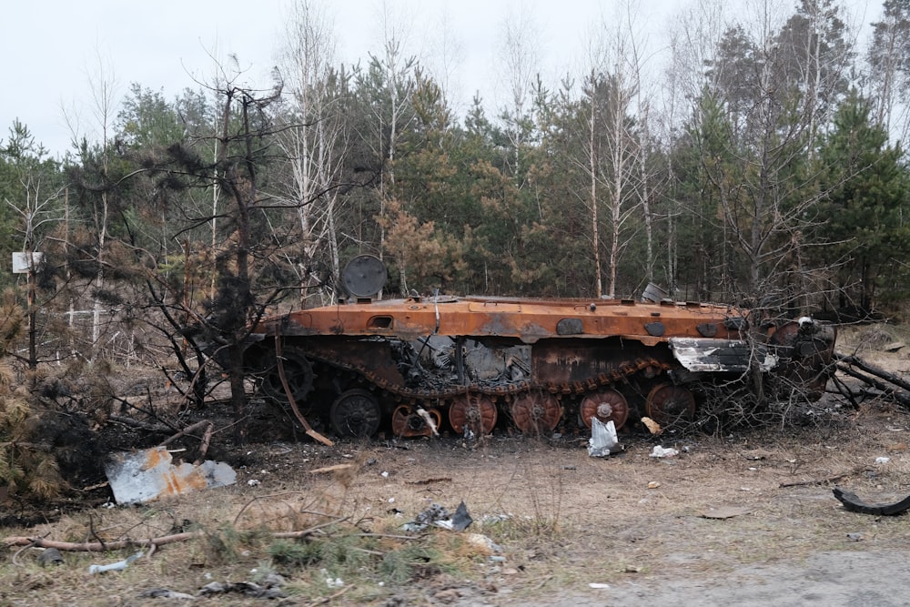 a rusted out truck sitting in the middle of a forest