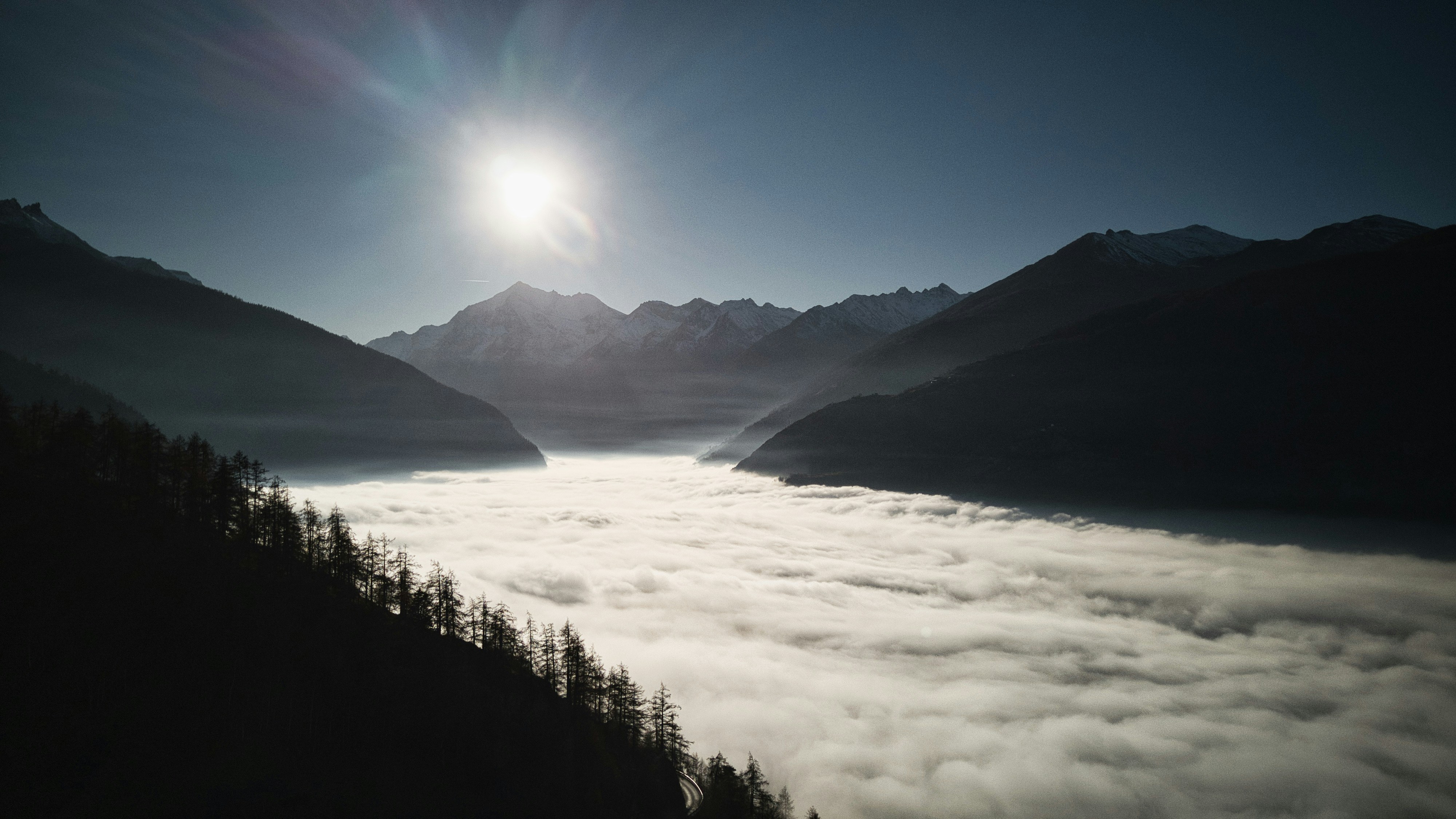 the sun is shining above the clouds in the mountains