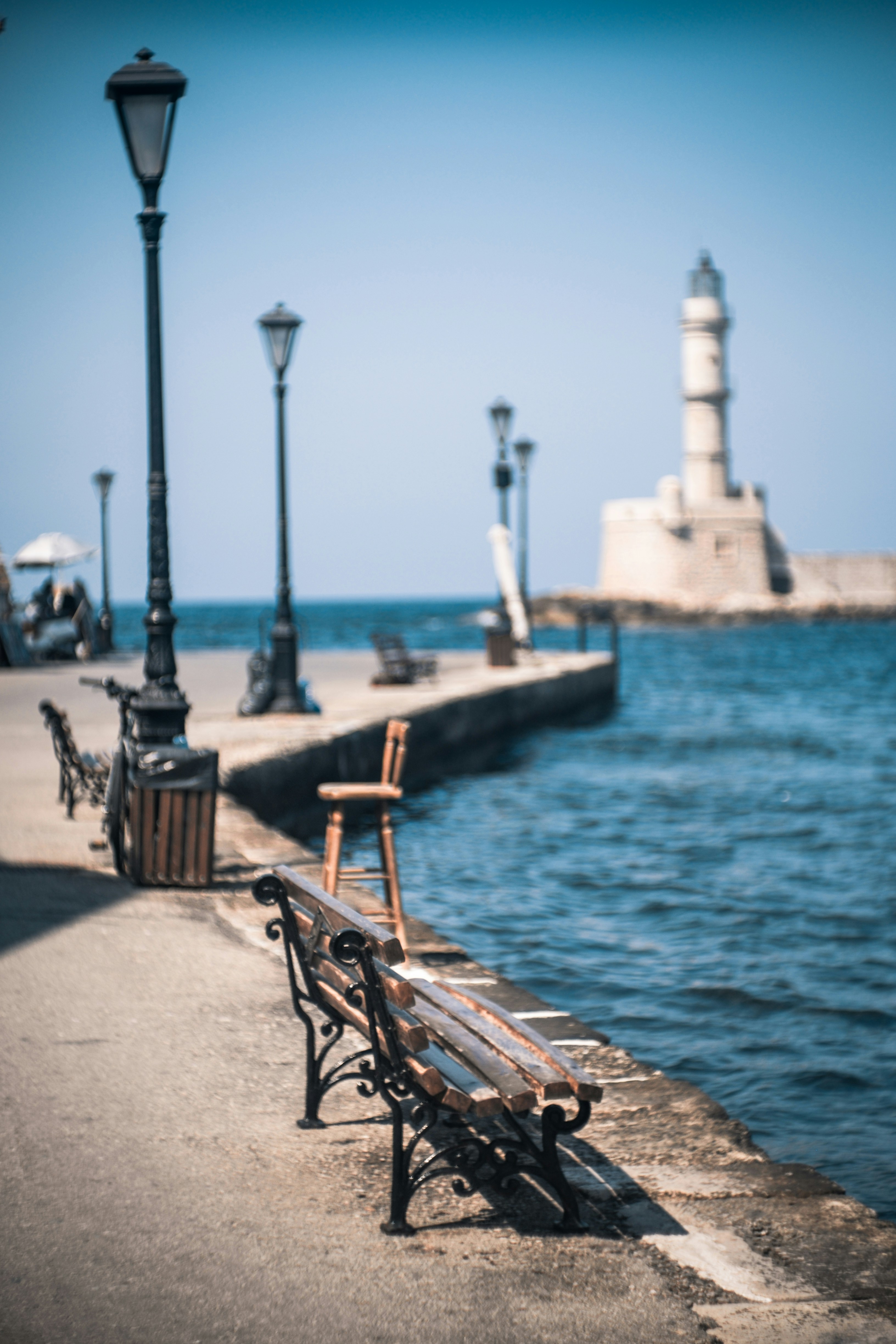 A wooden bench sitting next to a body of water photo – Free Χανία Image ...