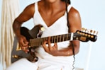 a woman playing a guitar while sitting on a chair