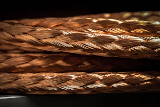 Close-up of copper electrical wires neatly coiled in a factory setting with warm lighting.