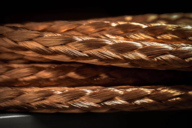 Close-up of copper electrical wires neatly coiled in a factory setting with warm lighting.