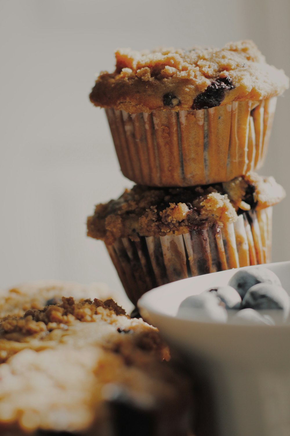 a stack of muffins next to a bowl of blueberries