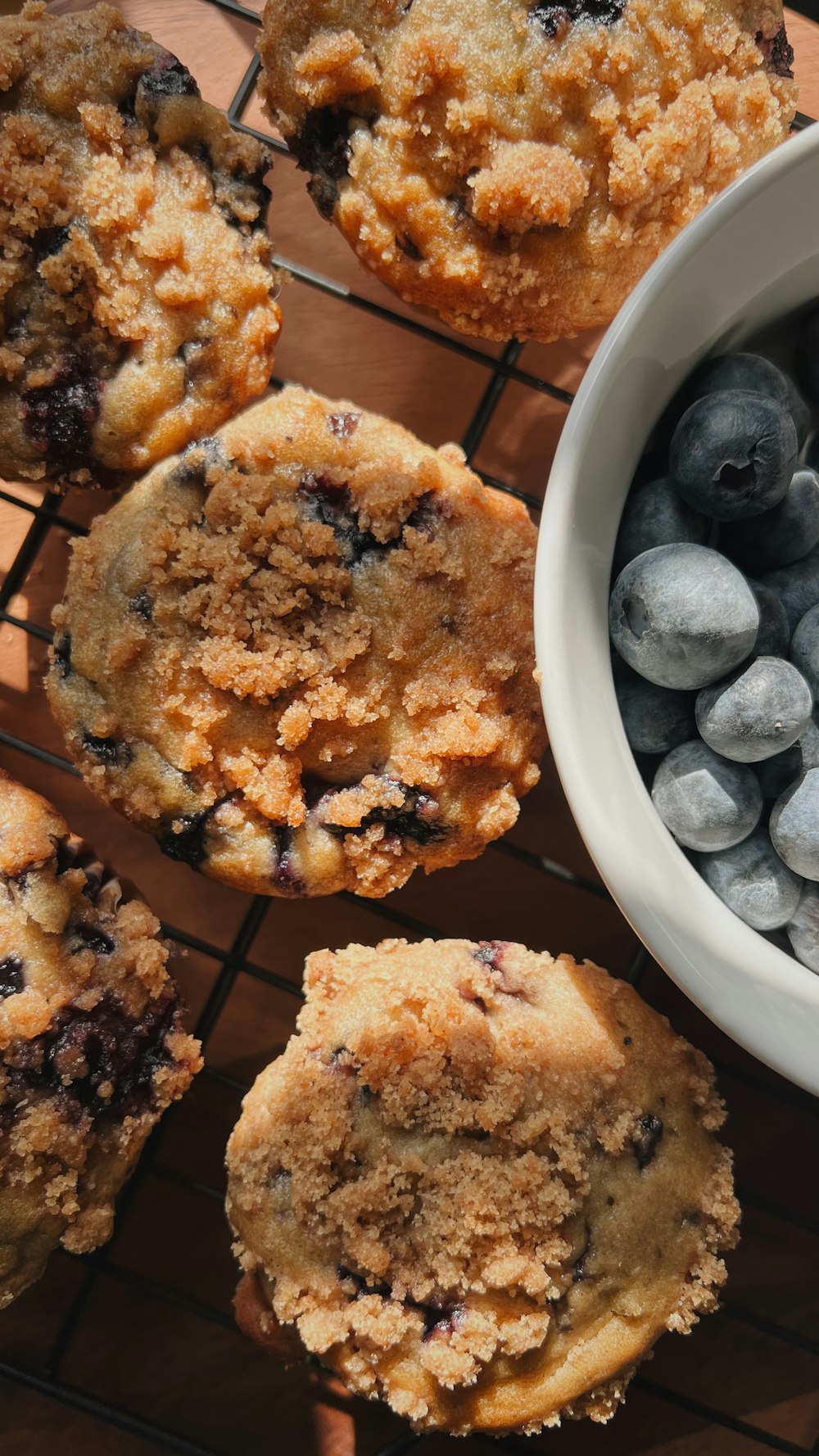 blueberry muffins and a bowl of blueberries on a cooling rack