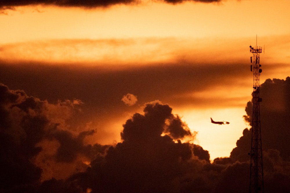 a plane flying through a cloudy sky at sunset