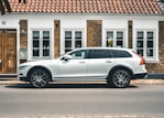 a white volvo car parked in front of a house