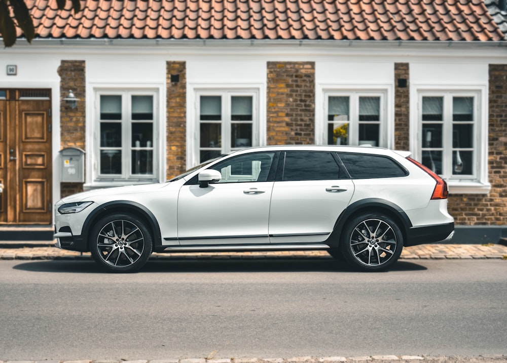 a white volvo car parked in front of a house