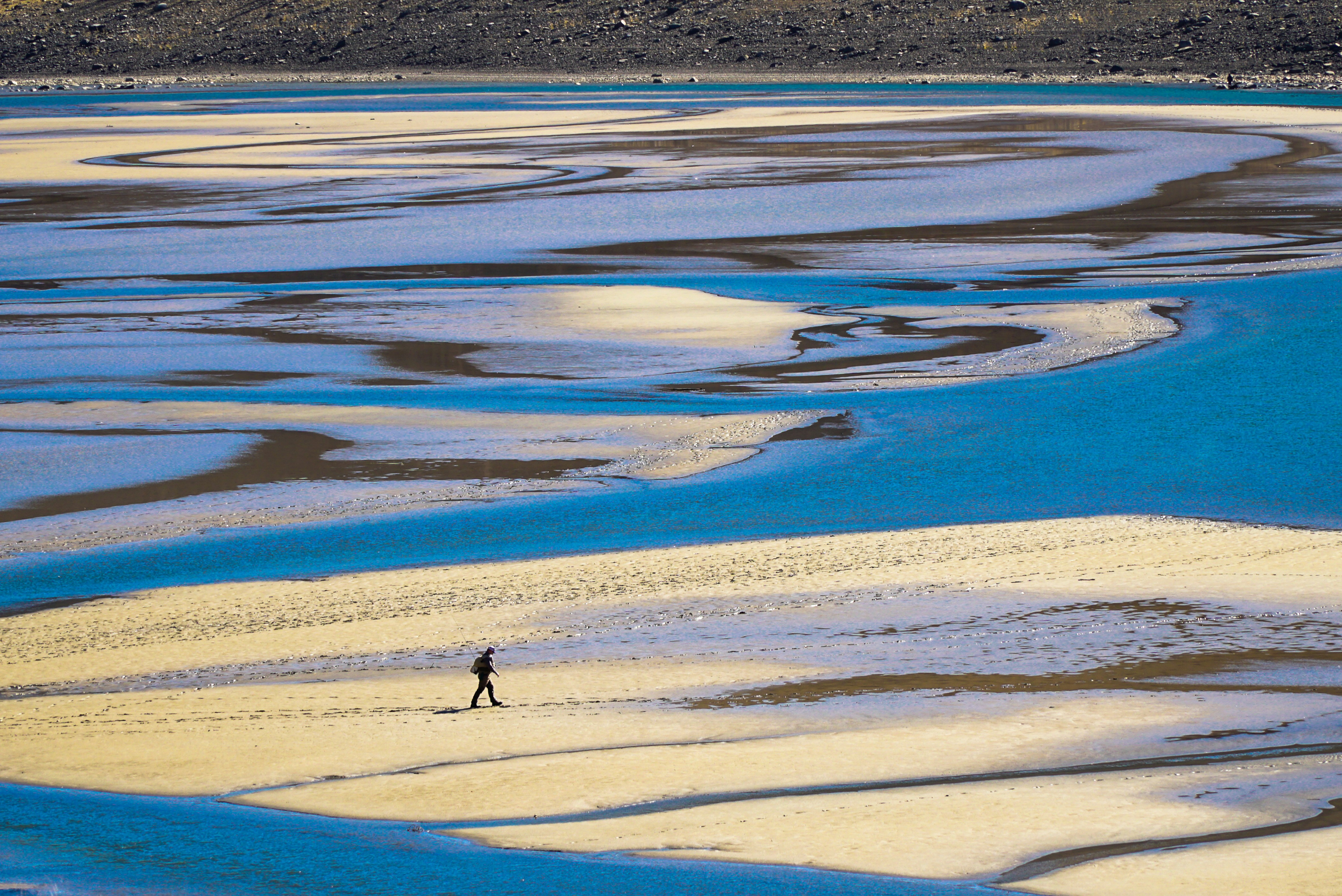 Ein Mann geht über einen Sandstrand neben einem Gewässer