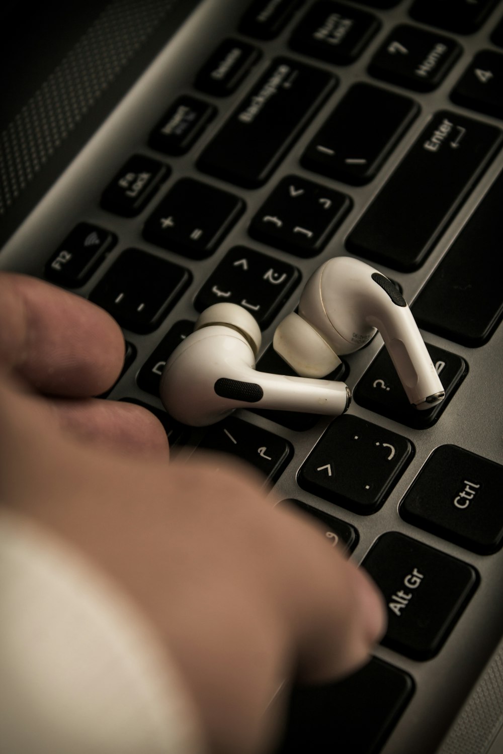 a pair of white ear buds sitting on top of a keyboard