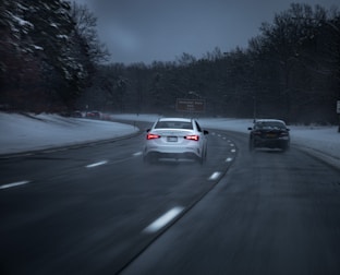 A snowy road scene with smart cars equipped with weather-adapt technology navigating safely.
