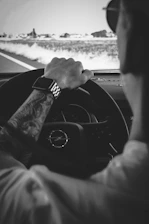 Black and white photo of a driving instructor guiding a student in a car.