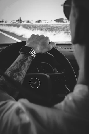 Black and white photo of a driving instructor guiding a student in a car.