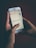 A person is holding a smartphone with both hands. The phone screen displays a message that reads, 'TIP FOR TODAY: Control how you respond to things sent to destroy your peace.' The background is dark, contrasting with the illuminated phone screen.