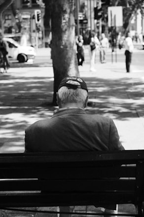 a man sitting on top of a bench next to a tree