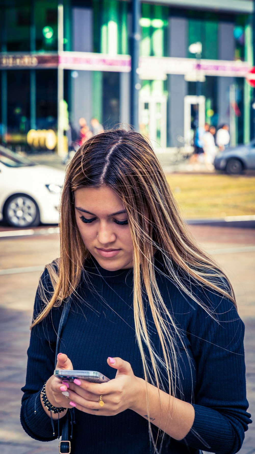 a woman standing on the street looking at her cell phone