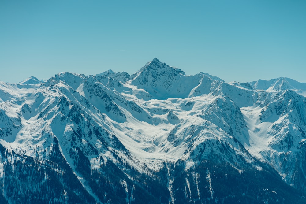 a mountain range covered in snow under a blue sky