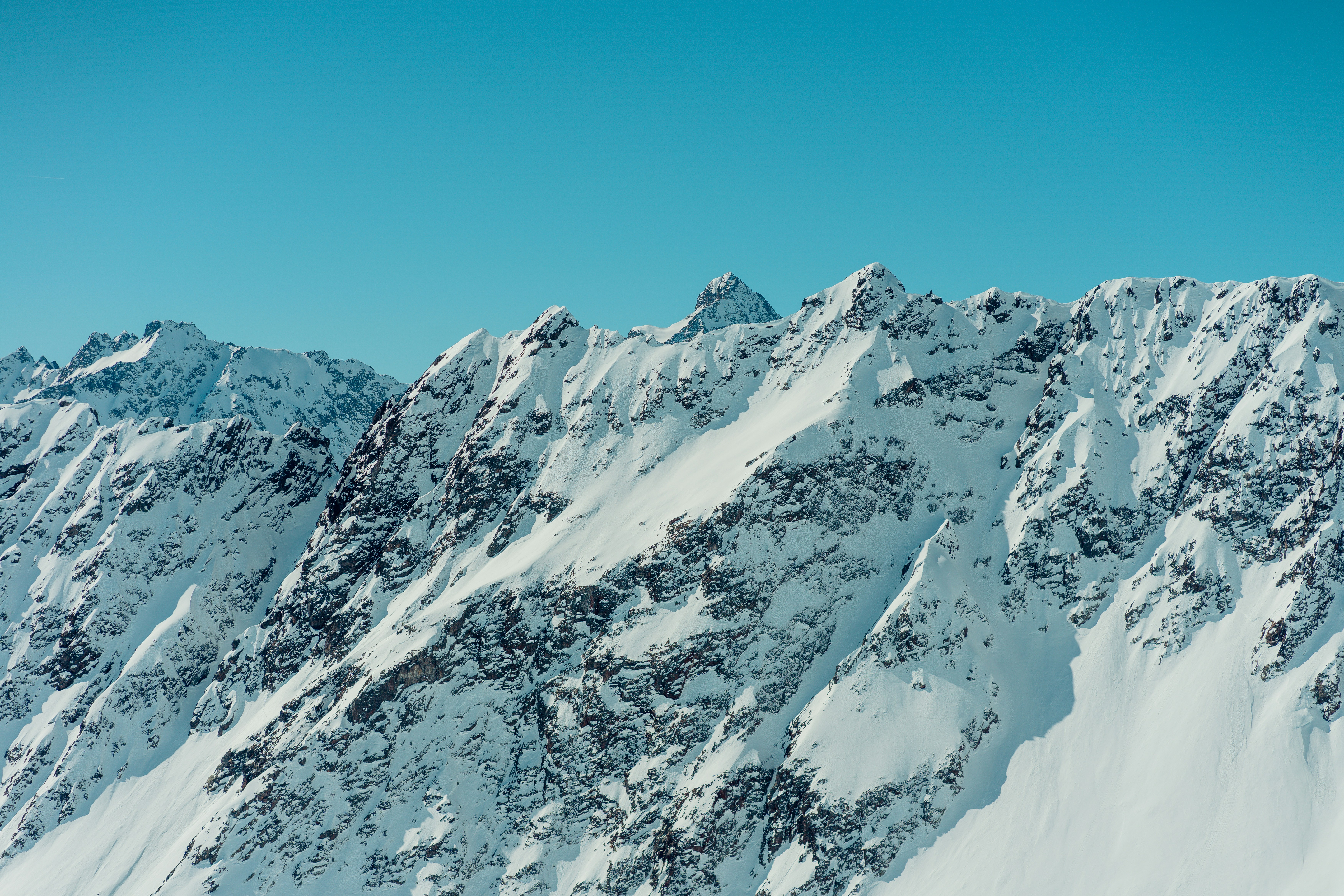 a large mountain covered in snow under a blue sky, 