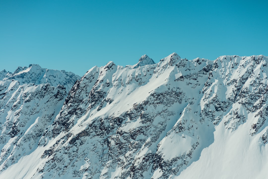 a large mountain covered in snow under a blue sky,