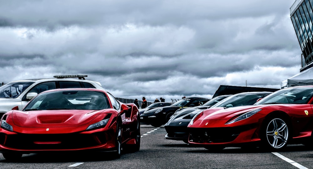 a row of red sports cars parked in a parking lot