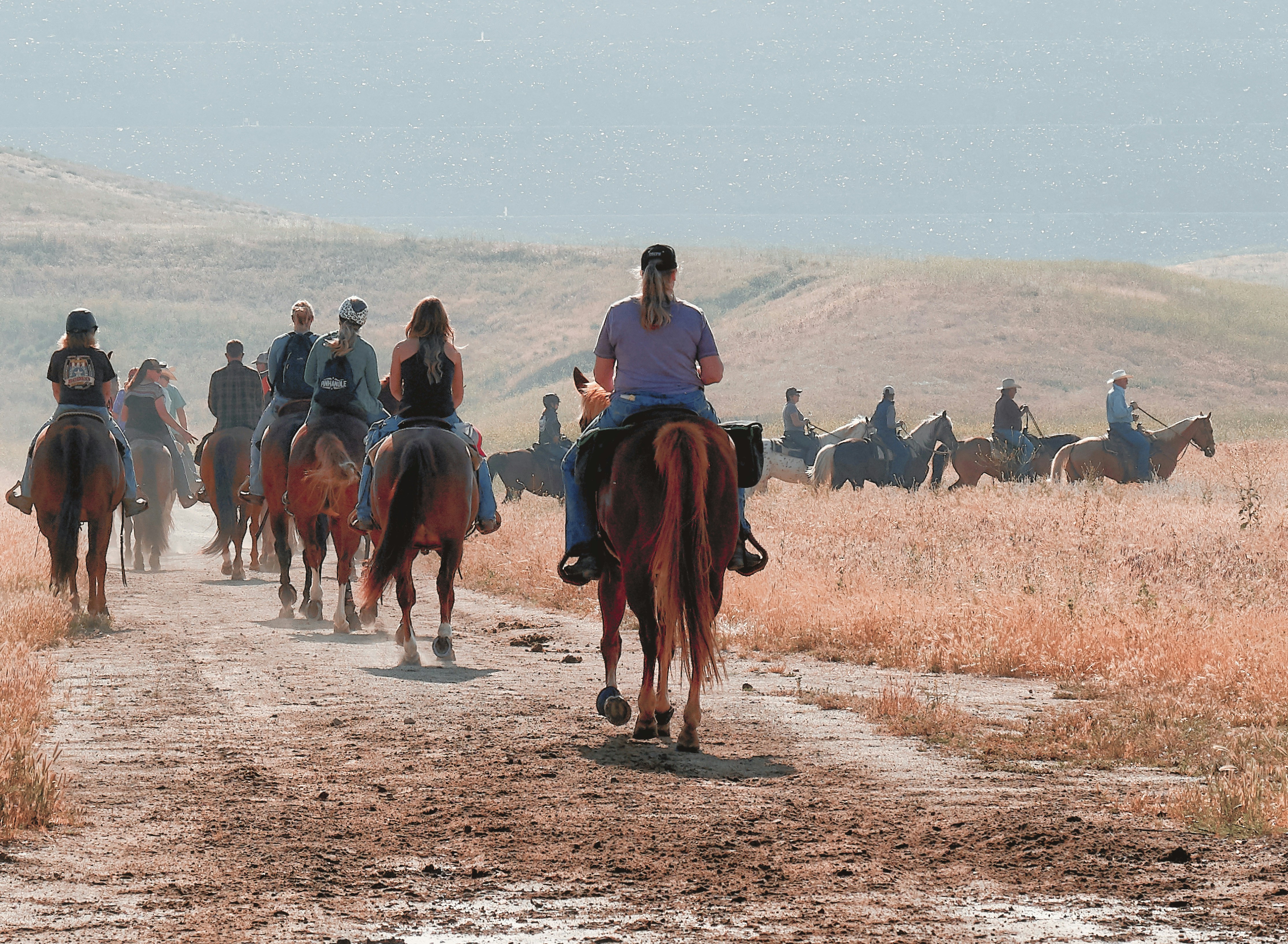 a group of people riding horses down a dirt road