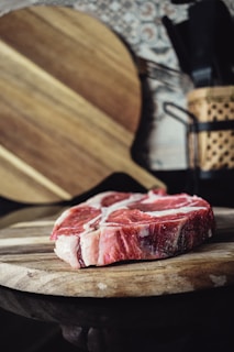 A close-up of fresh mutton pieces on a wooden cutting board.