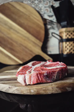 Close-up of a butcher expertly slicing a fresh cut of marbled beef on a wooden board.