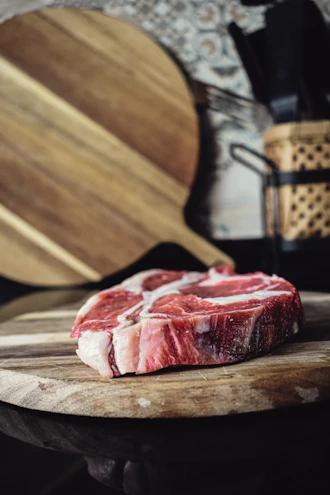Close-up of a marbled ribeye steak on a wooden cutting board.