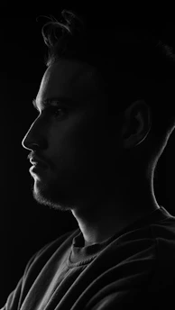 Side profile of a man with a sharp fade haircut under warm studio lighting.