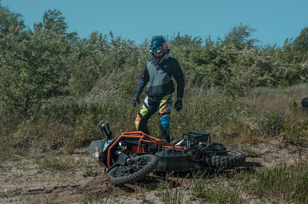 a man standing next to a motorcycle on a dirt road