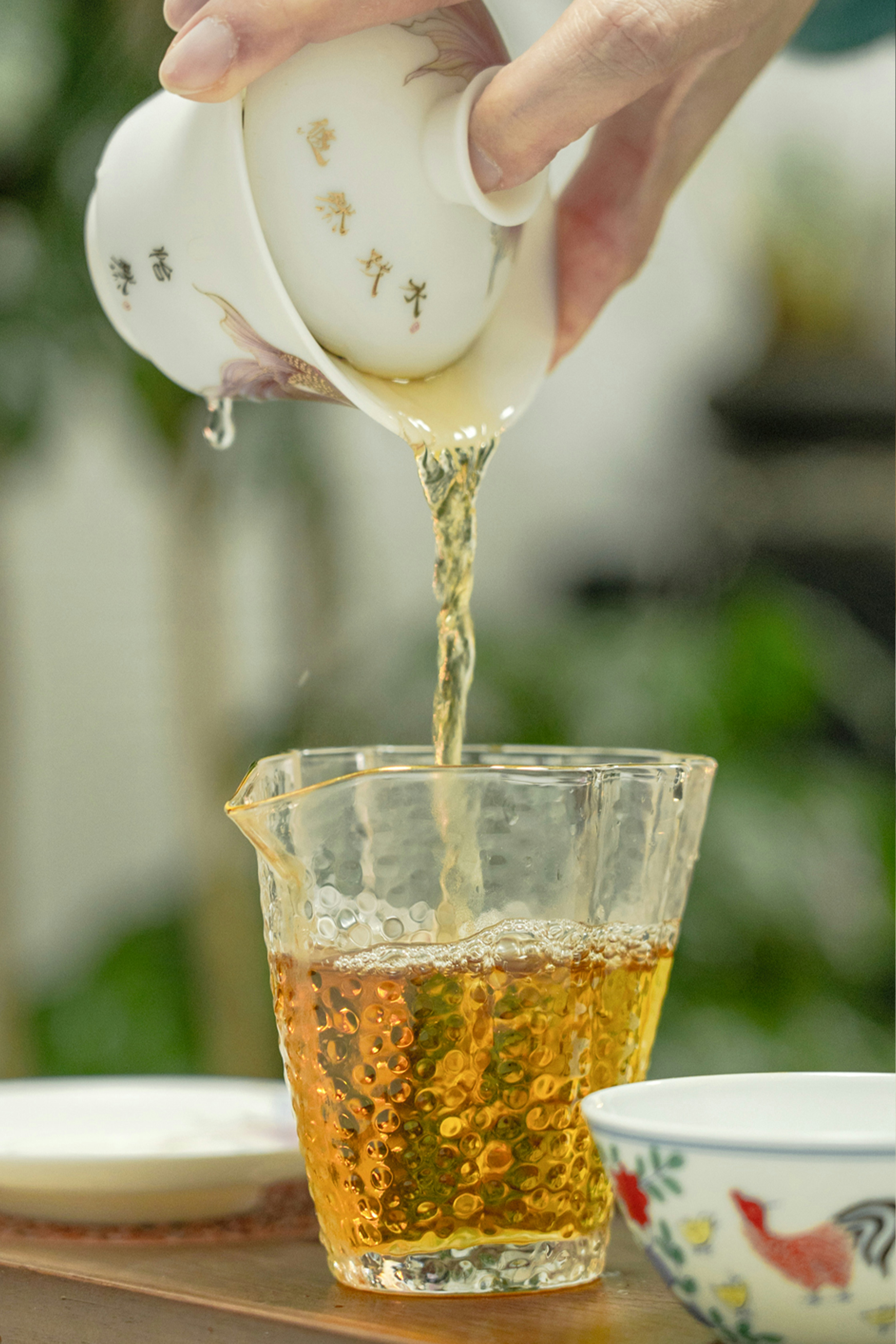 a person pouring tea into a glass cup