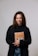 A smiling woman of diverse background holding a self-love book.