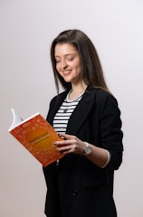 Portrait of Monica Mendez Leahy smiling warmly, holding one of her books.