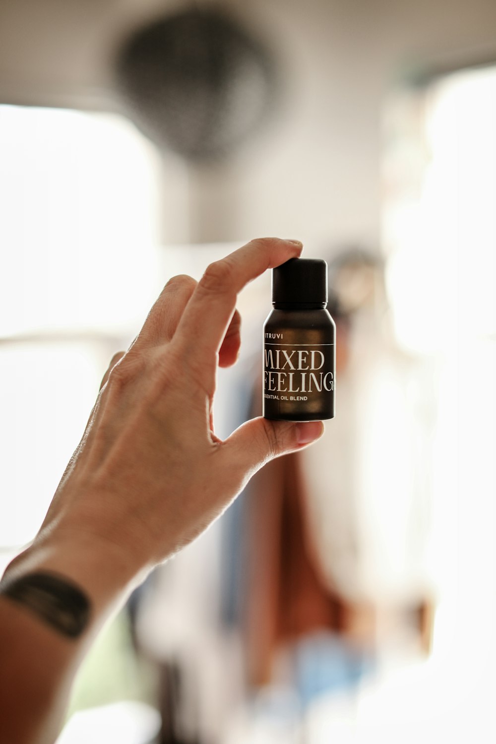 a person holding up a bottle of essential oil