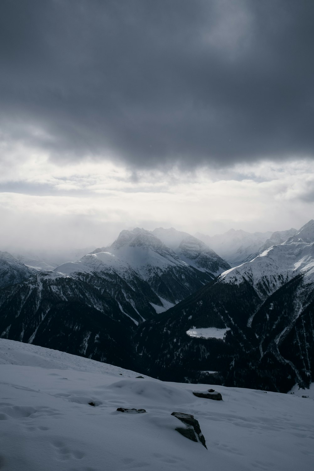 a view of a snowy mountain range under a cloudy sky