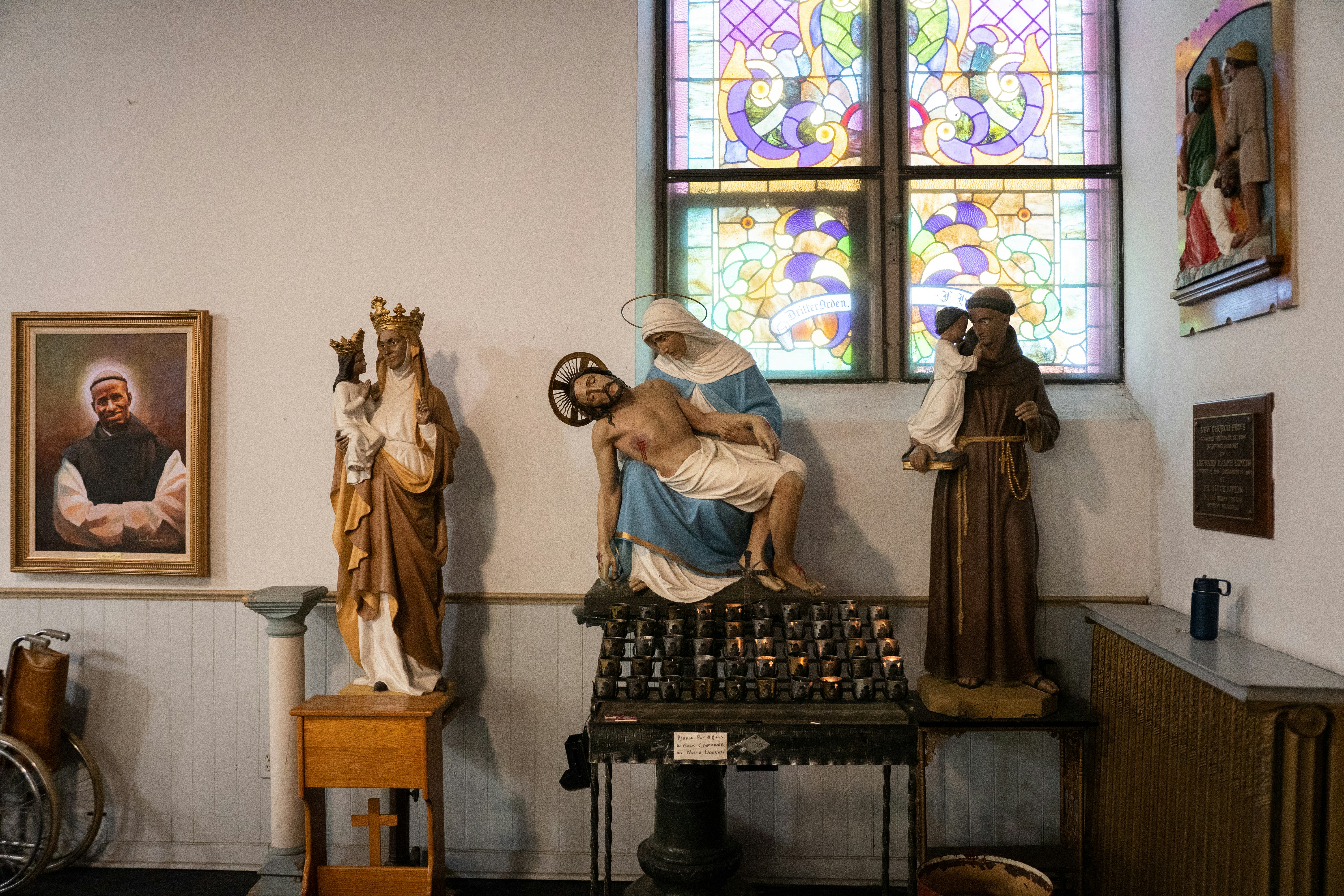 a statue of a person sitting on a bench in front of a stained glass window