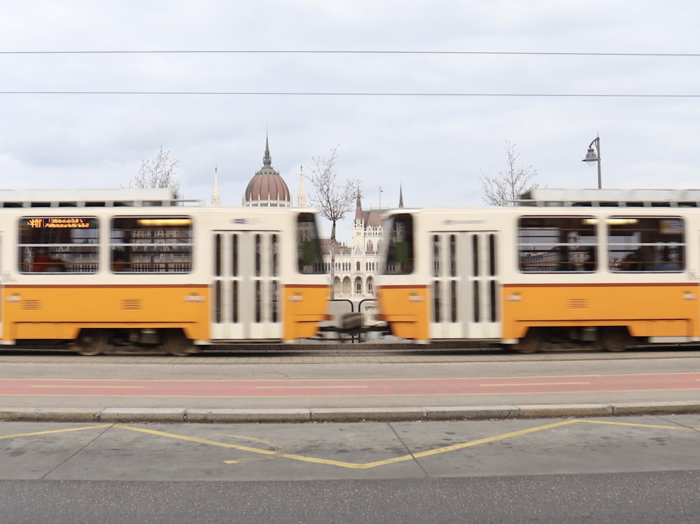 two yellow and white buses driving down a street