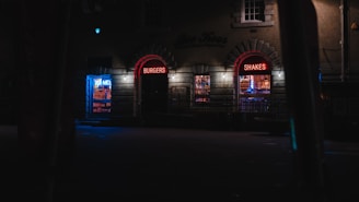 A vibrant storefront sign glowing at dusk on a busy El Paso street.