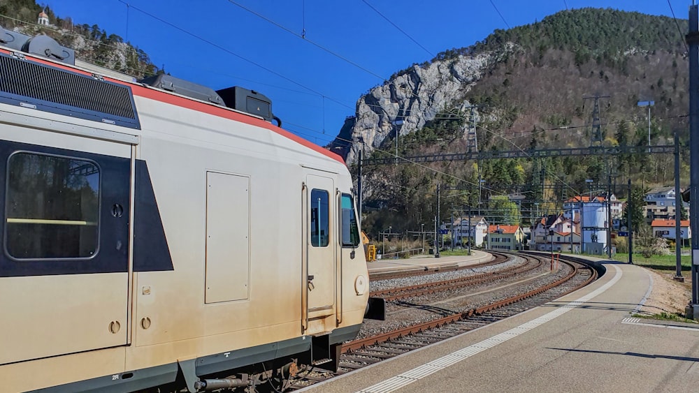 a train traveling down train tracks next to a mountain