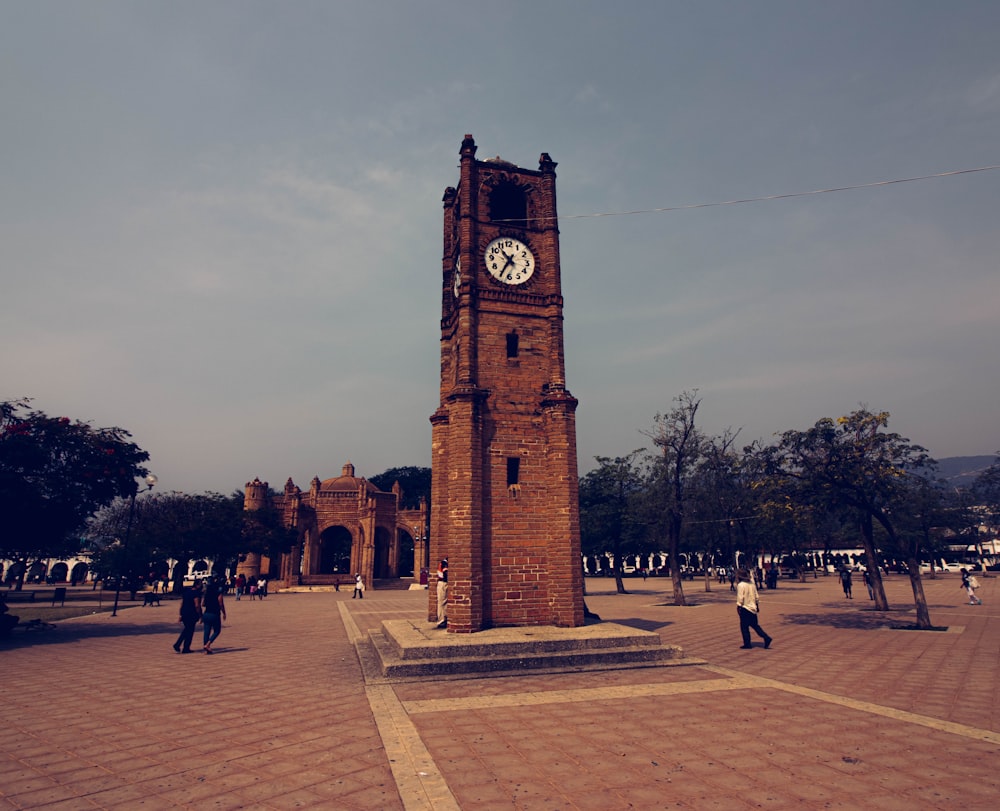 a tall brick clock tower sitting on top of a sidewalk