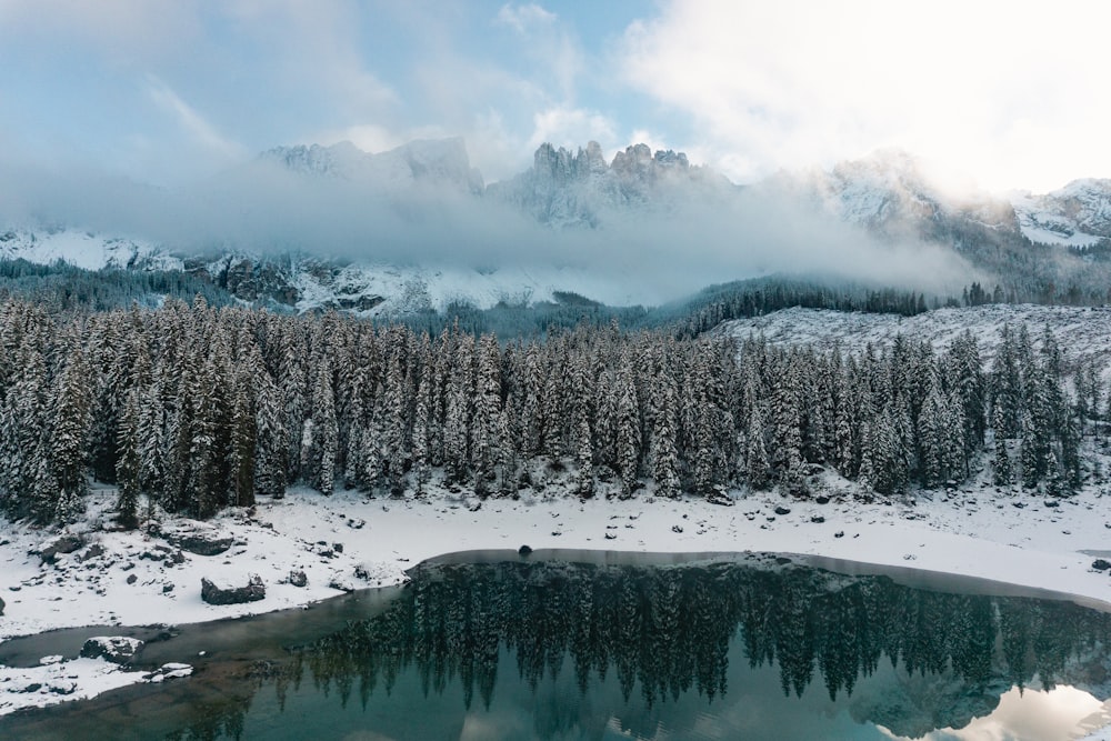 a lake surrounded by snow covered trees in the mountains