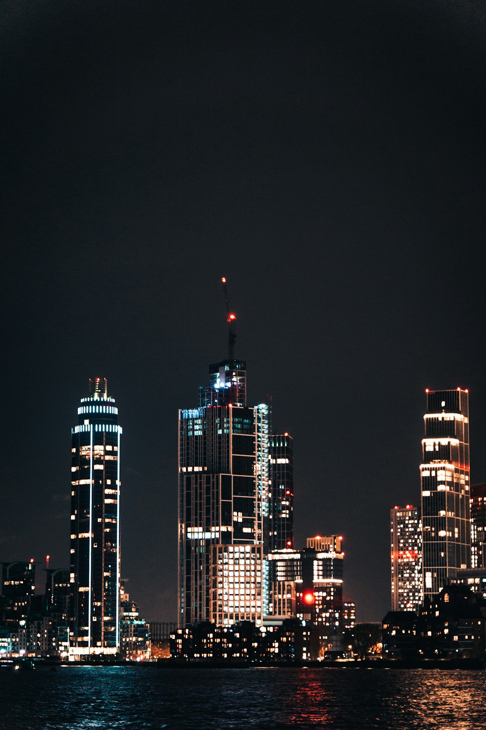 a city skyline at night with lights reflecting off the water