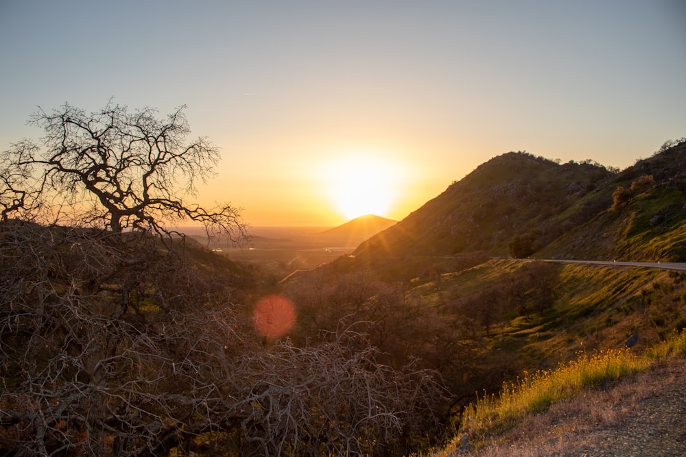 the sun is setting over the hills and trees