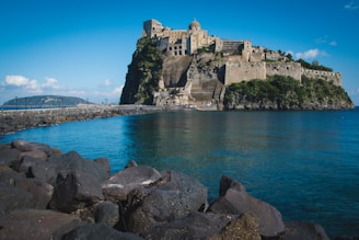a large castle sitting on top of a mountain next to a body of water
